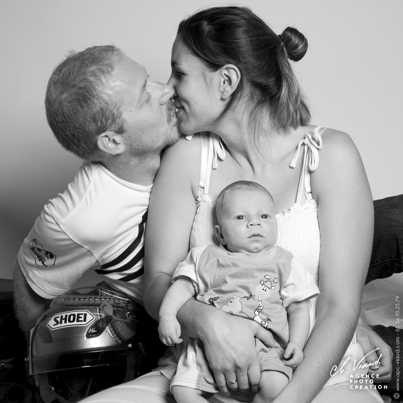 Photo de studio en noire et blanc d'une famille pour la naissance d'un bébé