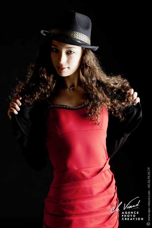 Photo studio d'une femme en robe rouge et un chapeau noir