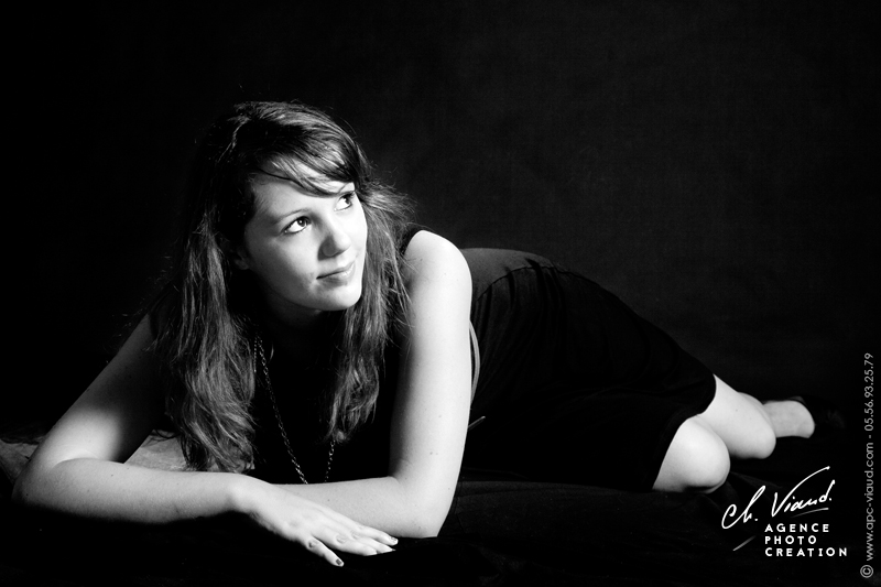 Portrait d'une femme en noir et blanc allongée dans un studio professionnel