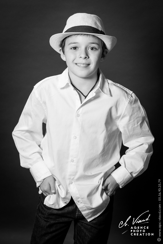 Portrait d'un garçon avec un chapeau et une chemise blanche dans un studio professionnel