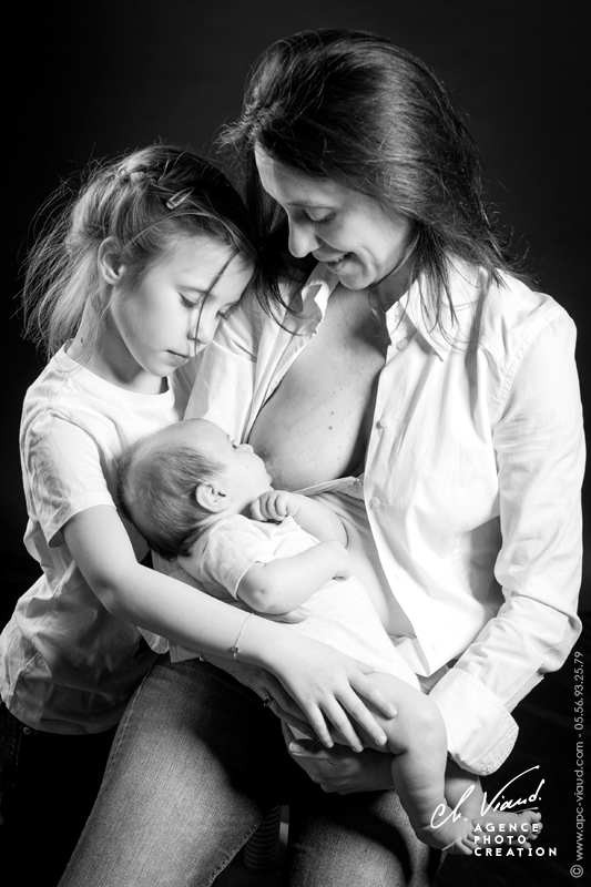 Portrait studio d'une mère allaitant son bébé sous les yeux de la grande sœur